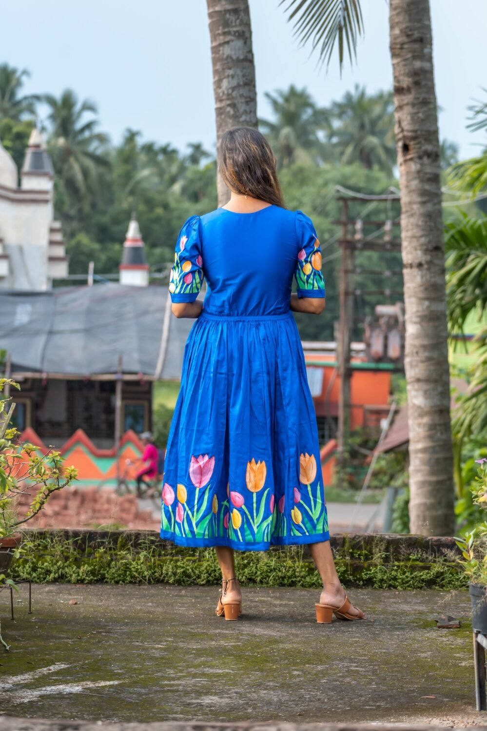 Back view of a woman wearing a royal blue hand-painted tulip dress.