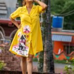 Model posing outdoors wearing bright yellow hand-painted storybook cottage tunic set.