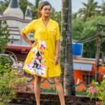Model posing with hand on hip showcasing yellow hand-painted tunic set with cottage artwork.