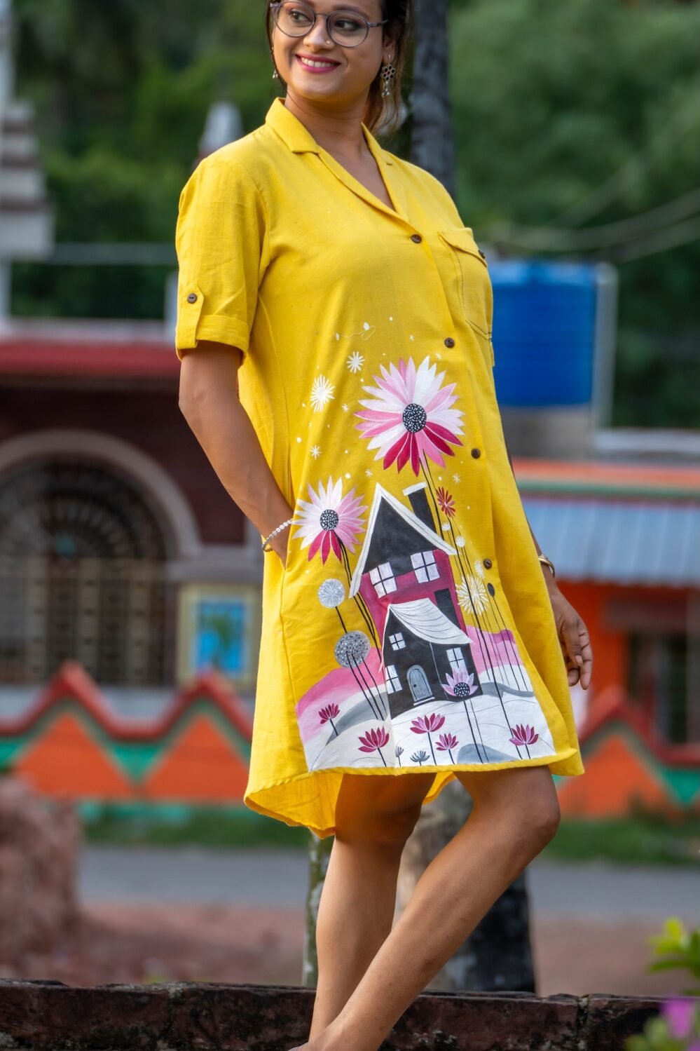 Model placing hand in pocket showing practical pocket design on yellow hand-painted tunic.