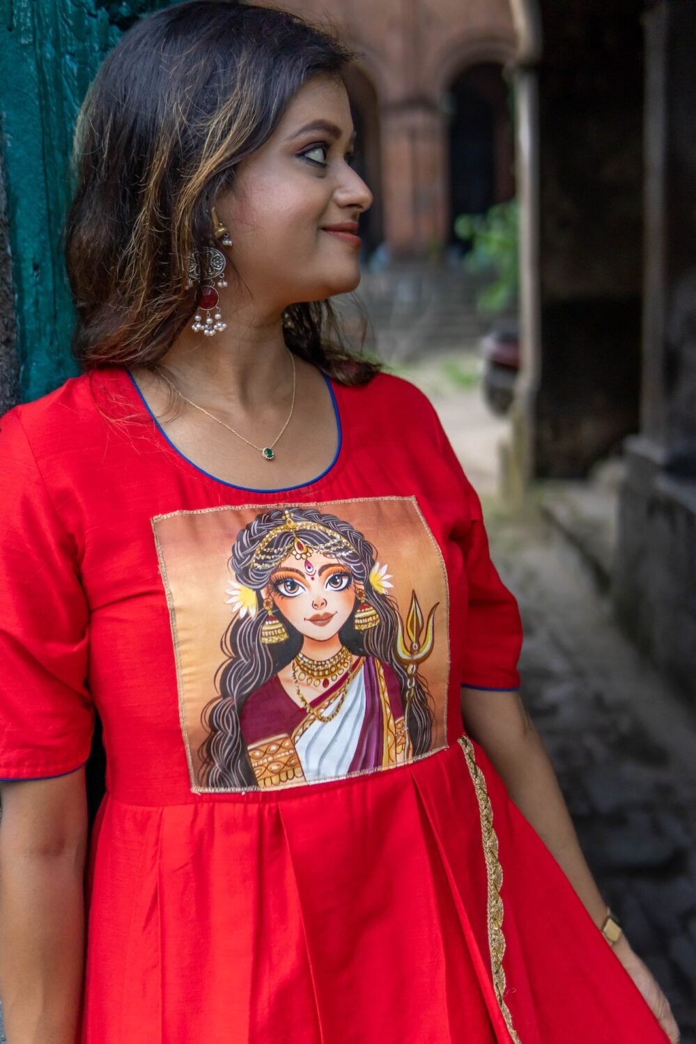 Detailed close-up of the hand-painted Maa Durga portrait on the red bodice of the gown.