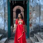 Model walking through a historical doorway wearing the red hand-painted Maa Durga gown.