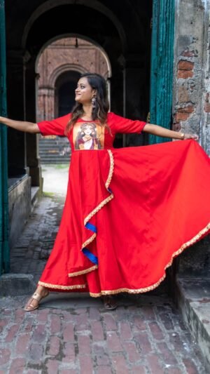 Model spreading the wide skirt flare of the hand-painted red Maa Durga gown in a doorway.