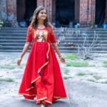 Full-length front view of model walking in the red hand-painted Maa Durga gown with blue piping.