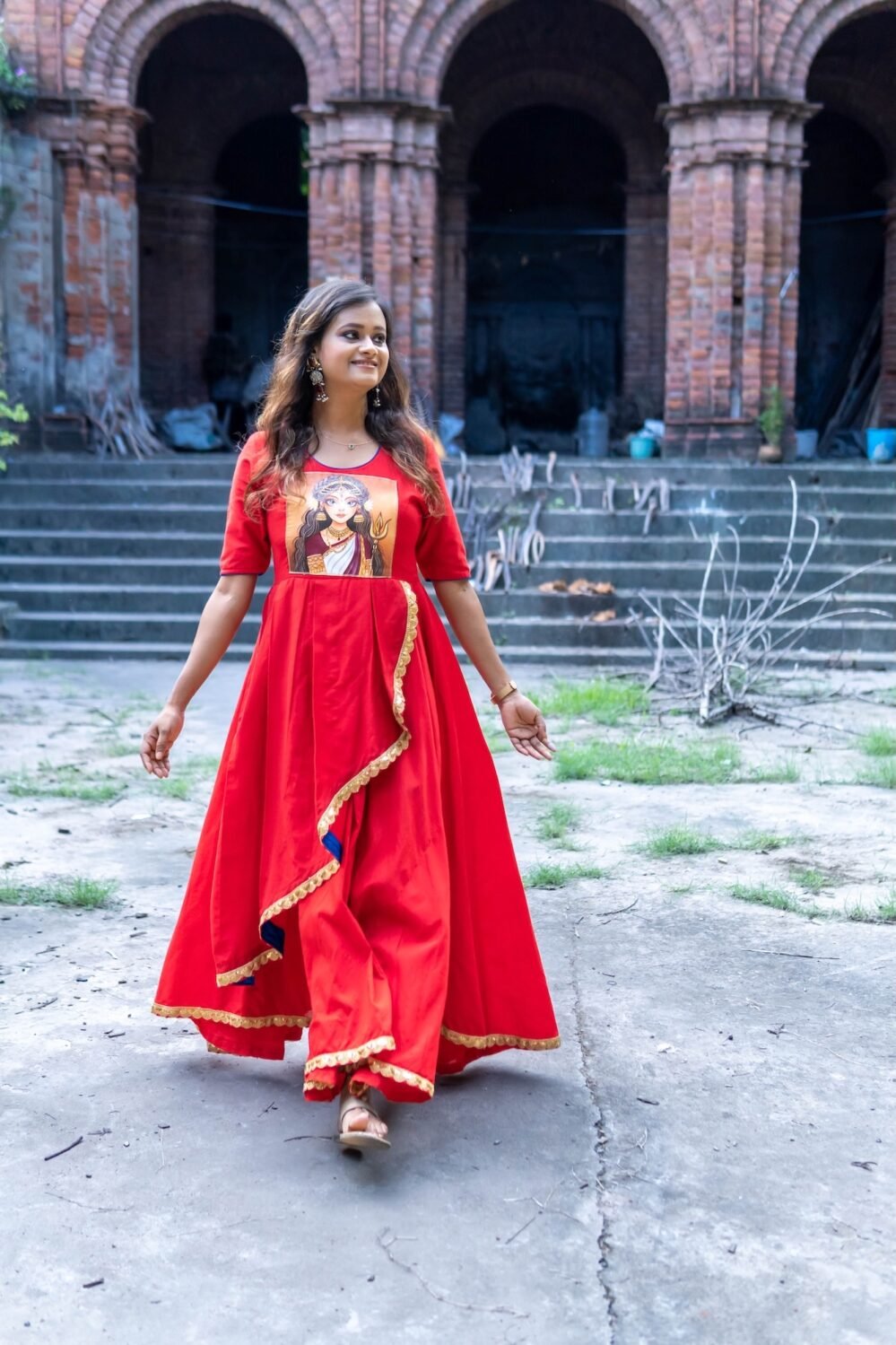 Full-length front view of model walking in the red hand-painted Maa Durga gown with blue piping.